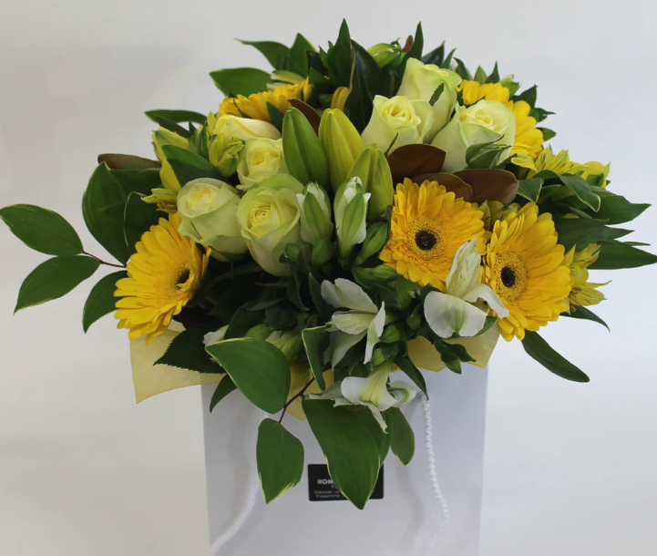 Bouquet of yellow and green flowers in a white vase on a light gray background
