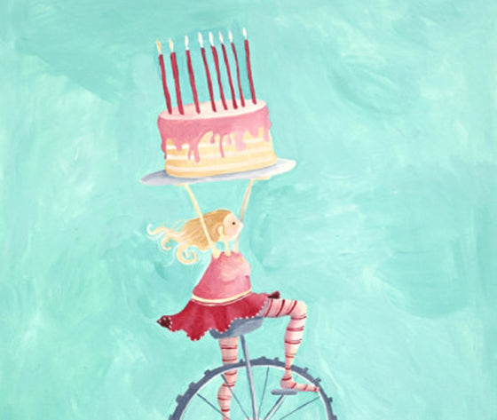 Girl riding a trike carrying a pink birthday cake